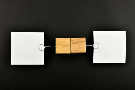 Opposite Opinion - Two white paper notes with wooden holders in different directions isolated on black paper background for presentationの写真素材