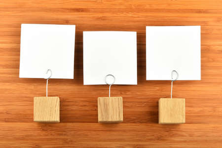 Three white paper notes with wooden holders on bamboo wooden background for presentationの写真素材