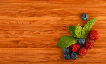 Taste of summer - cutting board with mellow blueberries, raspberries and mint leaves â add your textの写真素材