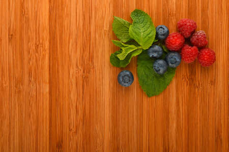Taste of summer - cutting board with mellow blueberries, raspberries and mint leaves â add your textの写真素材