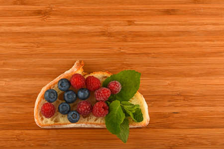 Better than caviar - cutting board with sandwich of mellow blueberries, raspberries and mint leaves on slice of wheat breadの写真素材
