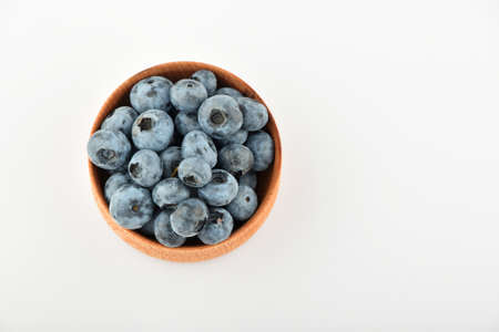 Handful of fresh blueberries in handmade wooden bowl isolated on white, top viewの写真素材