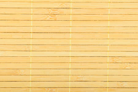 Bamboo wooden light yellow wicker braided mat with thread backgroundの写真素材