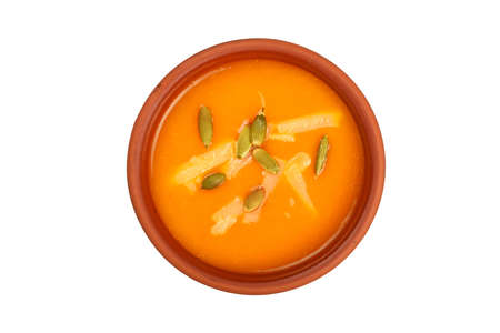 Ceramic bowl of pumpkin cream soup with seeds and cheese isolated on white background, top viewの写真素材