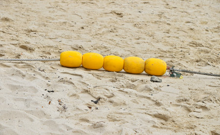 Four yellow polystyrene sea marker buoys group with cable tow on wet sand sea beach