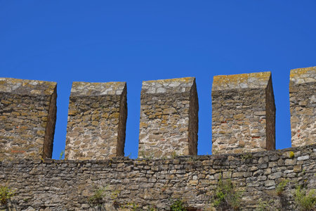 Medieval fortress or castle vallum, defensive stone wall over background of clear blue sky