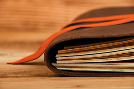 Handmade paper diary notebook in brown leather cover with orange bookmark over old vintage wooden...