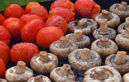 Vegetables in salt and spices being cooked on char grill, white champignons portobello mushrooms and red small tomatoesの写真素材