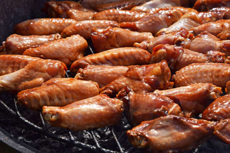 Chicken buffalo or teriyaki sauce raw wings cooked grilled on bbq smoke round grill, close upの写真素材