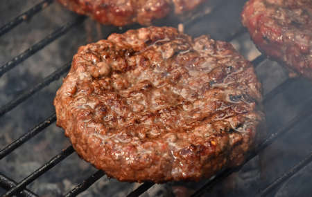 Beef or pork meat barbecue well done burgers for hamburger prepared grilled on bbq smoke grill, close upの写真素材