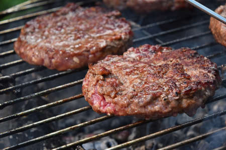 Beef or pork meat barbecue medium rare burgers for hamburger prepared grilled on bbq smoke grill, close upの写真素材