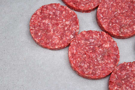 Raw red meat burgers for hamburgers of minced ground beef or pork on white parchment paper ready for cookingの写真素材