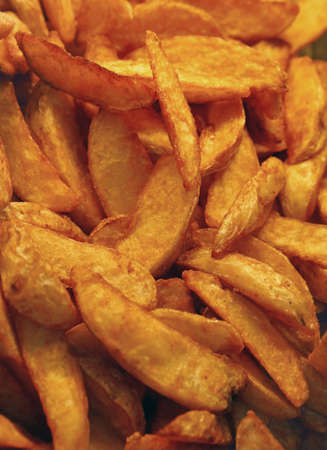 Unhealthy ready to eat deep fried potato or baked potato wedges chips with skins close up, high angle viewの写真素材