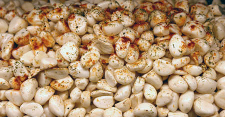 Pickled marinated white garlic chives, cloves or hops with red pepper and spices at retail market display, close up, high angle viewの写真素材