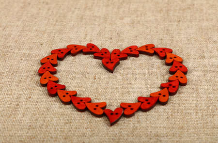 Red heart shaped handmade wooden sewing buttons frame on linen canvas, low angle view, close upの写真素材