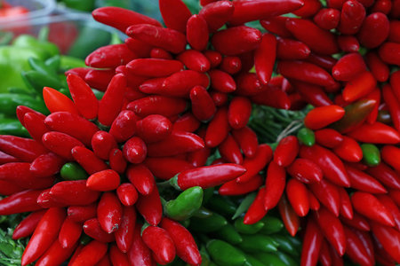Red hot chili and green jalapeno peppers bunches at retail farmers market stall display, close up...