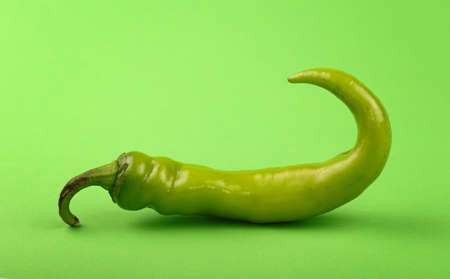 One whole fresh jalapeno hot chili pepper on green paper background, close up, low angle side viewの写真素材