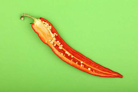 One cut half of fresh red hot chili pepper on green paper background, close up, elevated top viewの写真素材