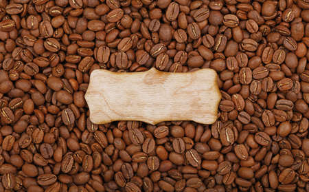 Blank rustic wooden sign over background of roasted brown Arabica coffee big beans pattern, close up, elevated top viewの写真素材