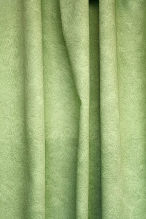 Heavy light green pleated felt textile curtain background with portiere drape folds, side view close upの写真素材