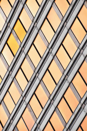 Orange colored glass windows of modern business office building at sunset in evening, diagonal perspective, low angle view, close upの写真素材