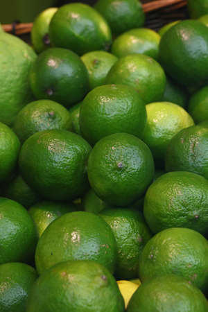 Heap of fresh green ripe lime fruits on retail market stall display, close up, high angle viewの写真素材