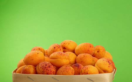 Fresh ripe mellow apricots in wooden wicker basket crate over background, close up, low angle side...
