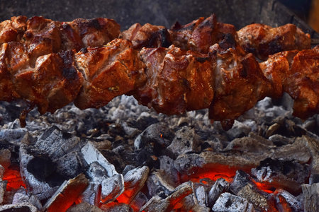 Close up of shish kebab churrasco beef meat cooked over char grill heat, low angle viewの写真素材