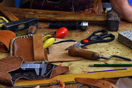 Working tools for leathercraft in wooden box on workbench desk, close up, high angle view