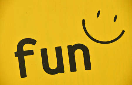 Word FUN and smile icon painted black on vivid yellow background, close upの写真素材
