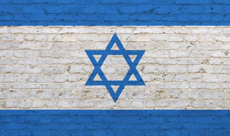 Old grunge vintage national flag of Israel graffiti style over background of white brick wallの写真素材