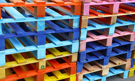 Close up stack of many vivid multicolor painted colorful wooden pallets, high angle diagonal viewの写真素材