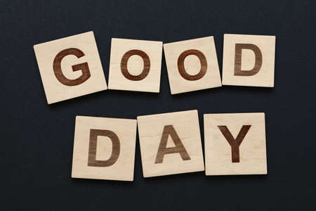Close up two words GOOD DAY on wooden letter signs over black board backgroundの写真素材