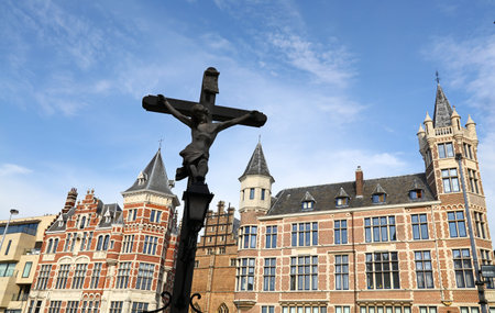 Low angle view of cross rood over old historical buildings and clear blue sky of Antwerp, Belgiumの写真素材