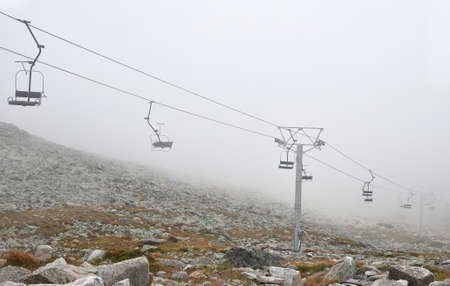 Mountain cableway chairlift in clouds and fog, high angle side viewの写真素材