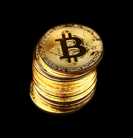 Close up stack of golden bitcoin physical coins isolated on black background with copy space, low...