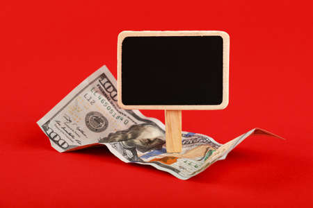 Close up one hundred US dollar paper currency banknote and blank chalk blackboard sign with copy space over red background, high angle viewの写真素材