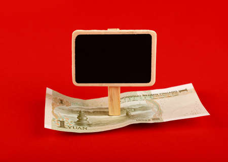 Close up one Chinese Yuan paper currency banknote and blank chalk blackboard sign with copy space over red background, high angle viewの写真素材