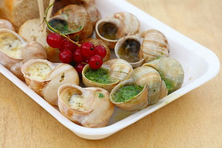 Close up street fast food take away portion of cooked escargot snails with French herbs and garlic...