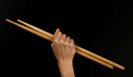 Close up woman hand with red nails holding two drumsticks over black background, side viewの写真素材
