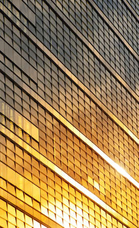 Orange colored glass windows of modern business office building at sunset in evening, diagonal perspective, low angle viewの写真素材