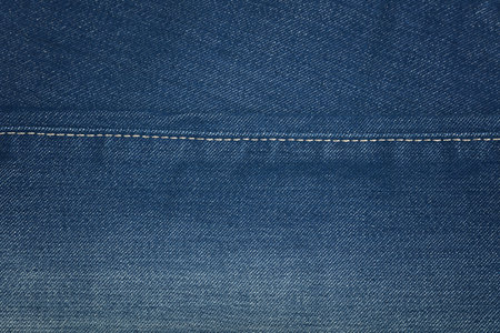 Dark indigo blue washed cotton jeans denim texture background with stitching seam edge line, close...