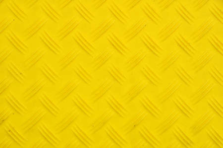 Vivid yellow industrial anti slip embossed plastic plate with diagonal bumps of diamond pattern texture, background, close upの写真素材