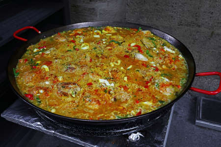 Close up cooking traditional Spanish Valencian mixed paella with chicken, seafood and vegetables in big frying pan, high angle viewの写真素材