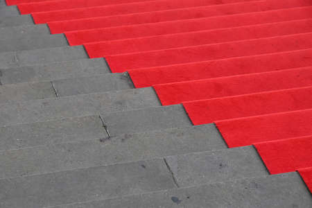 Close up red carpet over grey concrete stairs perspective ascending, high angle viewの写真素材