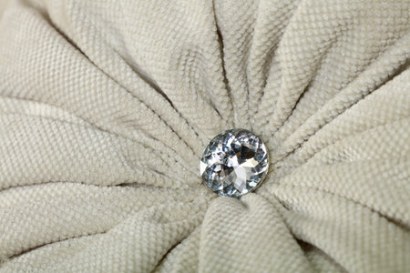 Close up diamond shaped crystal strass or rhinestone decoration on grey beige furniture textile...