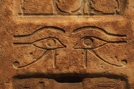 Close up background of antique stone wall with carved ancient Egyptian bas relief of wadjet, Eye of Ra or Horus, front viewの写真素材