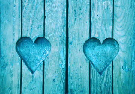 Close up two heart shapes, symbol of love and romance, wood carved in blue painted wooden window shutterの写真素材