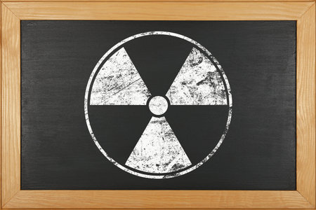 White chalk radioactive hazard warning sign over grunge black background of chalkboard with copy spaceの写真素材