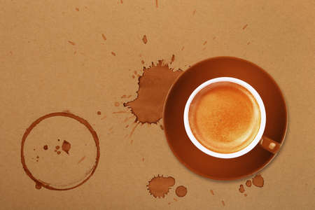 Brown cup full of espresso coffee on saucer, with ring coffee stains and drops on brown paper parchment background, elevated top view, directly aboveの写真素材
